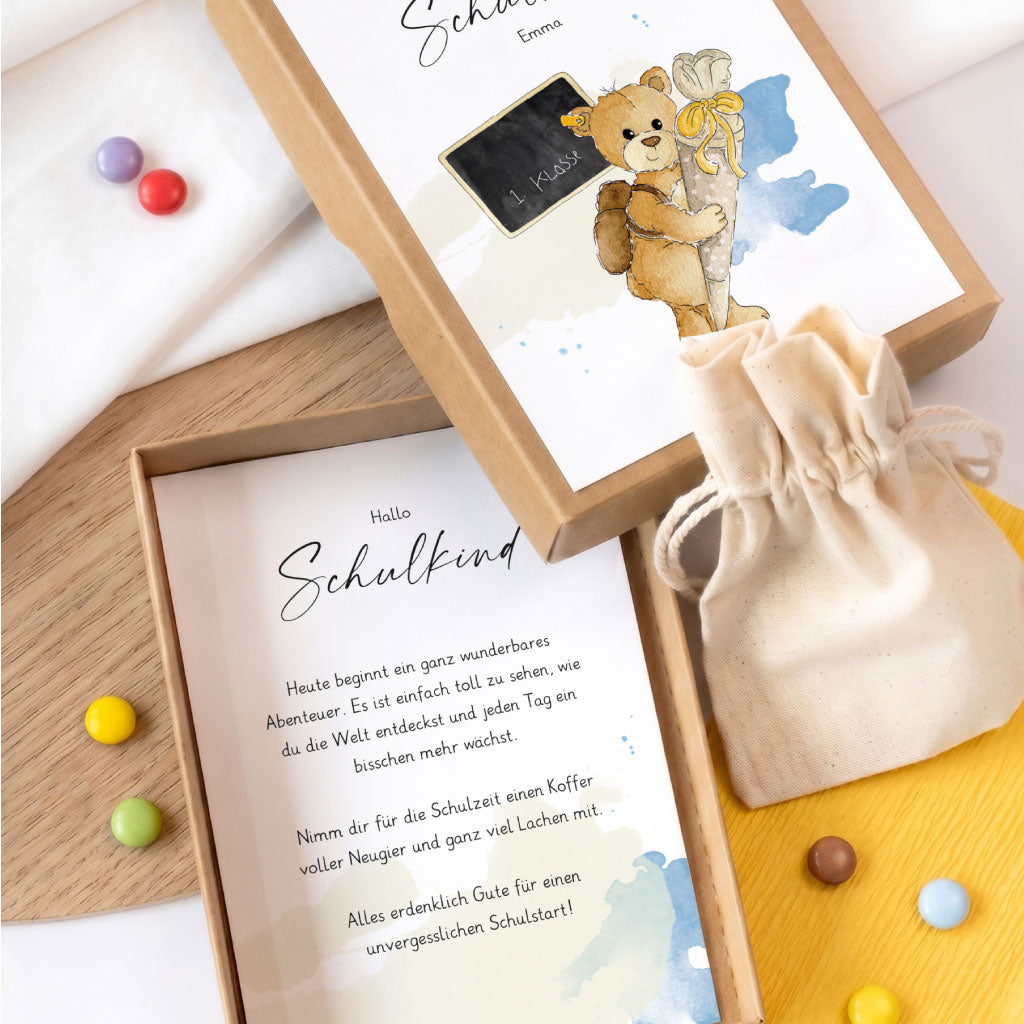 Offene Geschenkschachtel zum Schulanfang mit liebevollem Text im Inneren und kleinem Baumwollbeutel für das Geldgeschenk.