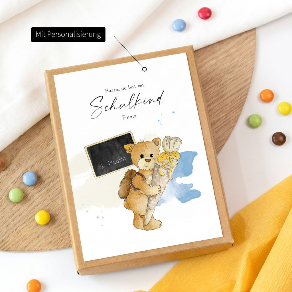 Personalisierte Geschenkidee zur Einschulung mit Wunschnamen und niedlichem Teddy Aquarell Motiv auf der Geschenkschachtel.