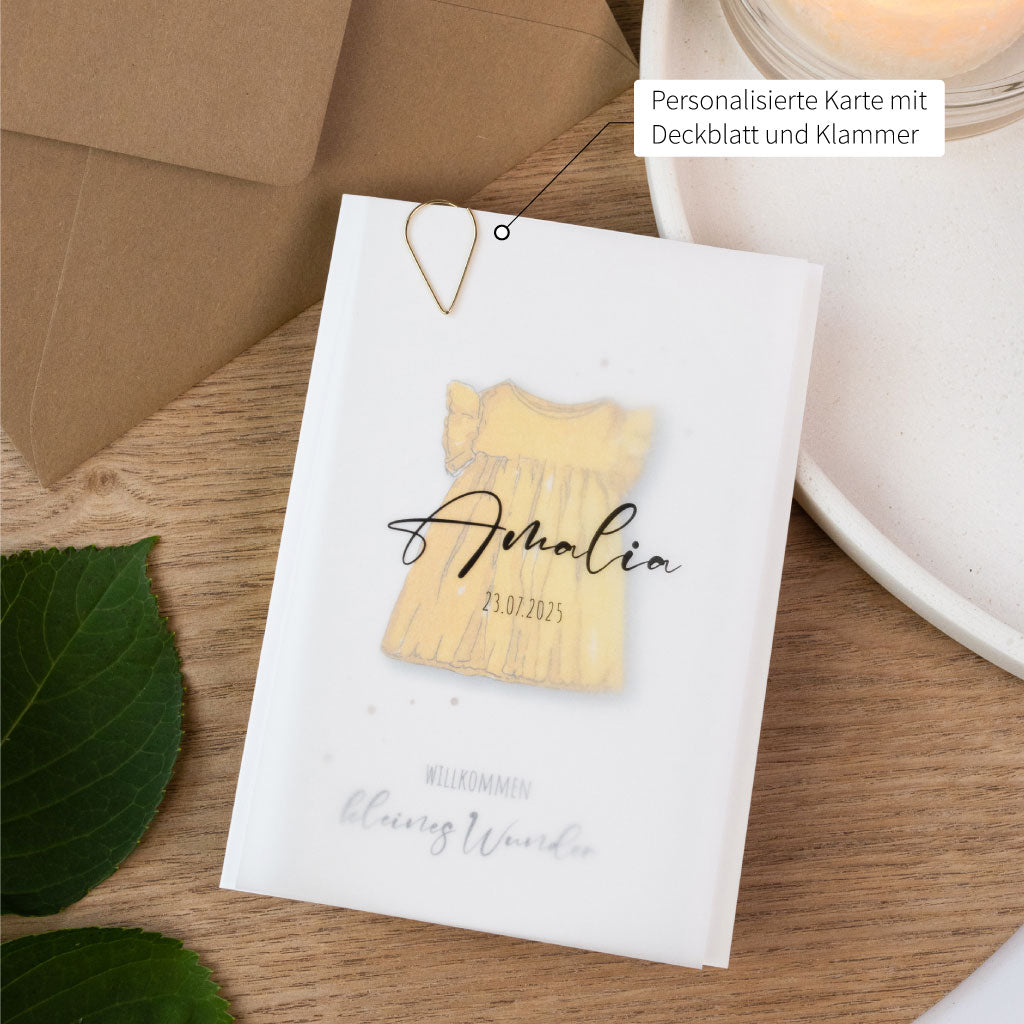 Babykarte zur Geburt mit zartem gelbem Kleid im Aquarellstil, individuell gestaltbar mit Namen und Datum, veredelt durch ein transparentes Deckblatt und goldene Klammer.