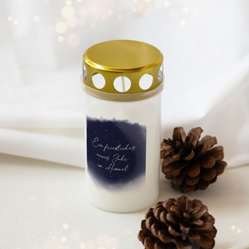 Grabkerze zu Silvester mit goldenem Deckel und dunkelblauem Himmelmotiv, verziert mit dem Spruch „Ein friedliches neues Jahr im Himmel“