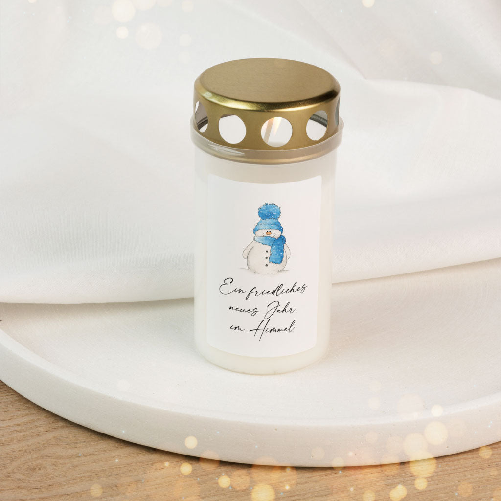 Weiße Grabkerze mit goldenem Deckel und handgemaltem Schneemann-Aufkleber, Text „Ein friedliches neues Jahr im Himmel“, als Andenken zu Silvester und Neujahr für Sternenkinder.