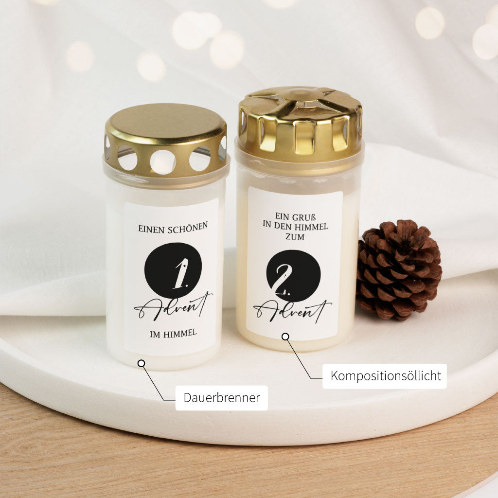 Nahaufnahme zweier Grablichter mit den Aufdrucken „1. Advent im Himmel“ und „2. Advent“ sowie Beschriftung der Varianten „Dauerbrenner“ und „Kompositionsöllicht“ – persönliche Gedenkkerzen für Sternenkinder oder erwachsene Verstorbene.
