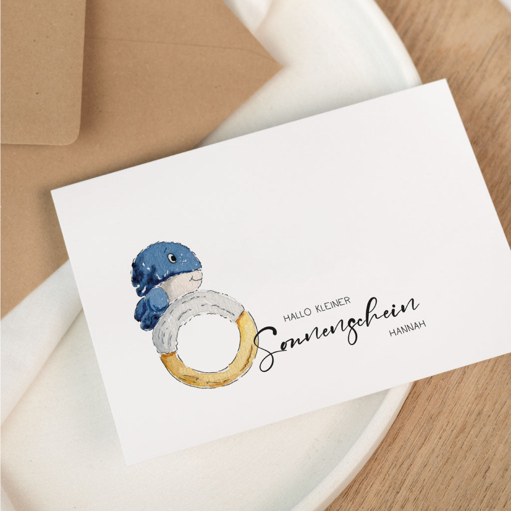 Personalisierbare Glückwunschkarte zur Geburt eines Baby mit handgemaltem Wal-Baby Motiv und Schriftzug „Hallo kleiner Sonnenschein“ auf weißer Karte.