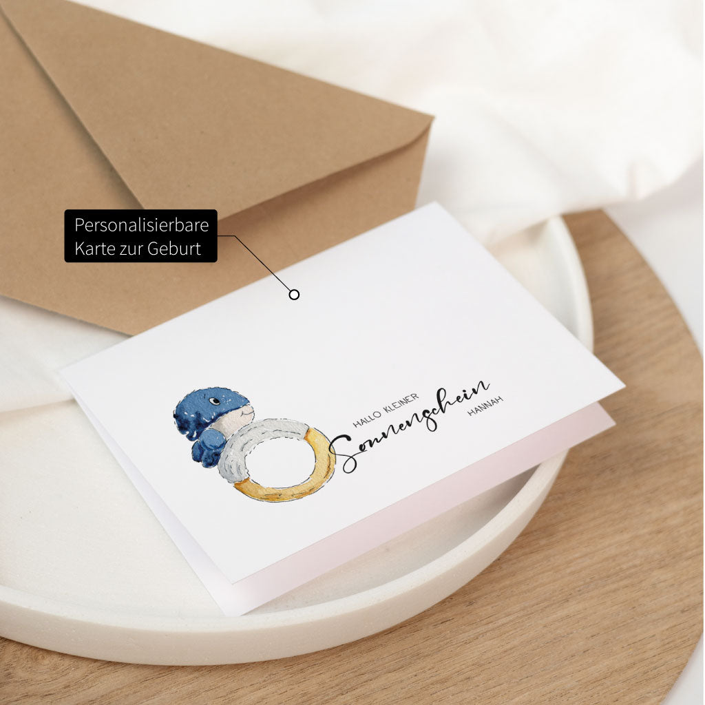 Geburt Baby Karte mit Umschlag: personalisierbare Glückwunschkarte zur Geburt mit Wal-Baby Illustration auf dem Kartenformat, liegend auf einem Tablett.