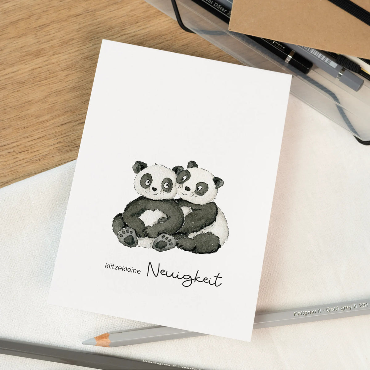Schwangerschaftskarte mit zwei handgemalten Aquarell Pandas die sich umarmen und dem Schriftzug klitzekleine Neuigkeit