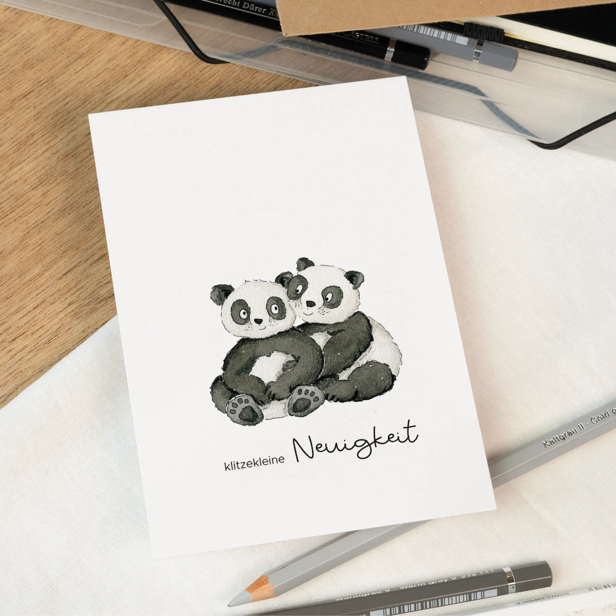 Karte zur Schwangerschaftsverkündung mit handgemalten umarmenden Pandas und Schriftzug klitzekleine Neuigkeit