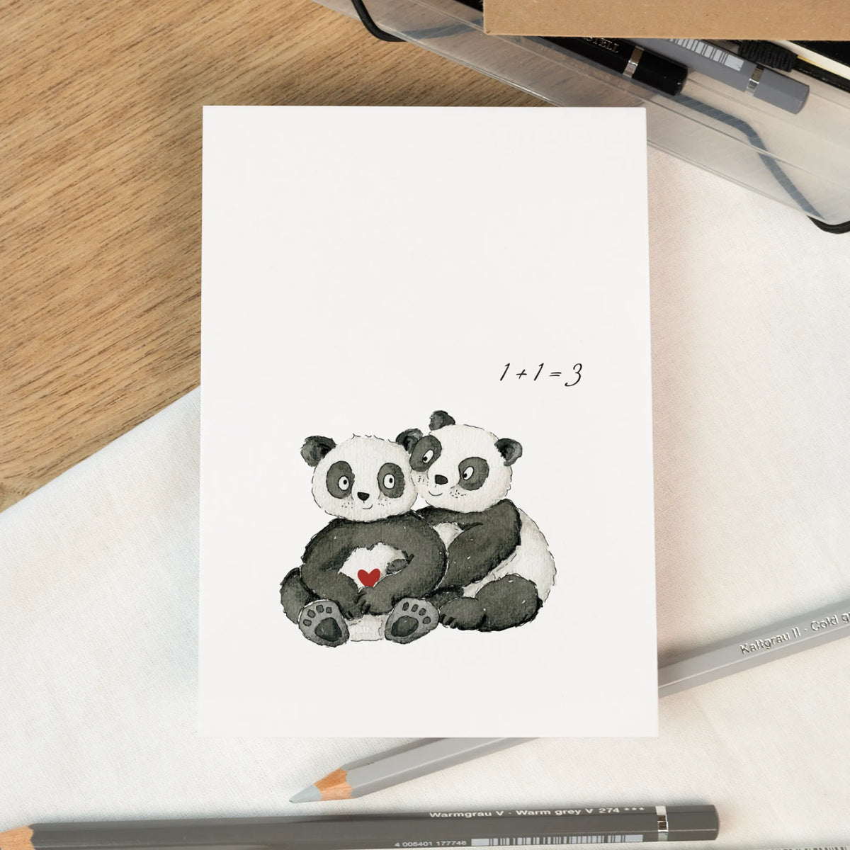 Schwangerschaftskarte zur Verkündung mit zwei handgemalten Pandas und rotem Herz, Aufschrift 1+1=3, auf hellem Untergrund