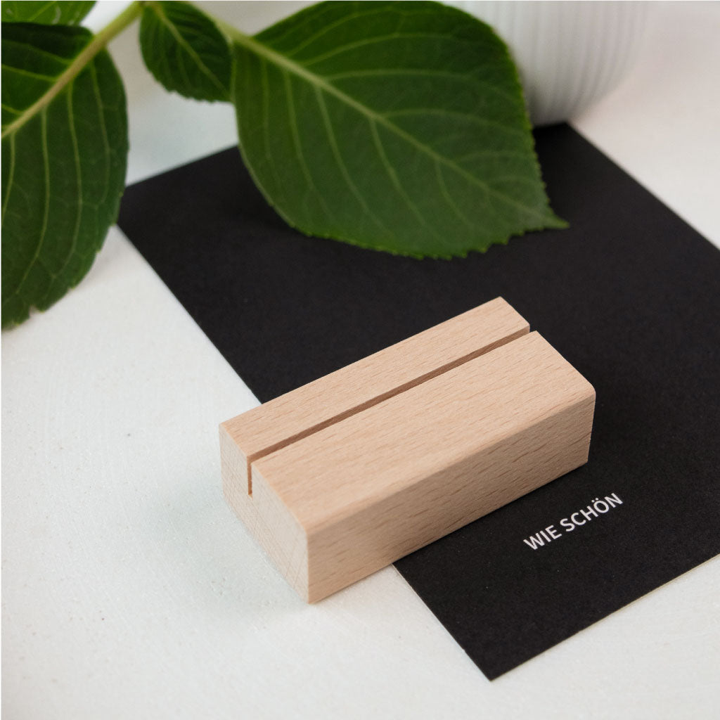Detailaufnahme eines schlichten Kartenständers aus Buche, platziert auf einer schwarzen Karte.