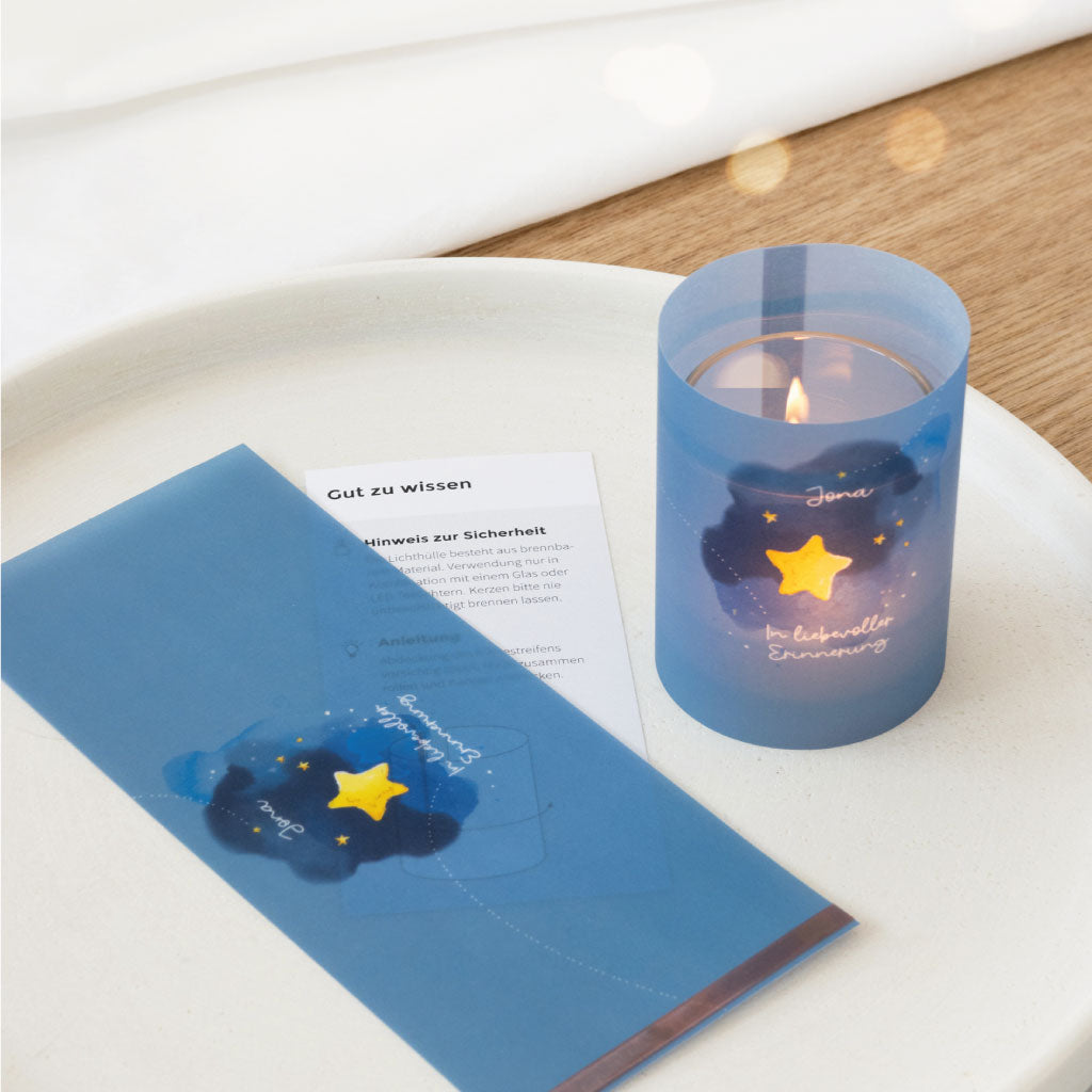 Lichthülle mit Kerze im Glas auf weißem Teller, daneben Anleitung – liebevoll gestaltetes Andenken mit handgemaltem Motiv für Sternenkinder oder Trauerfeiern.