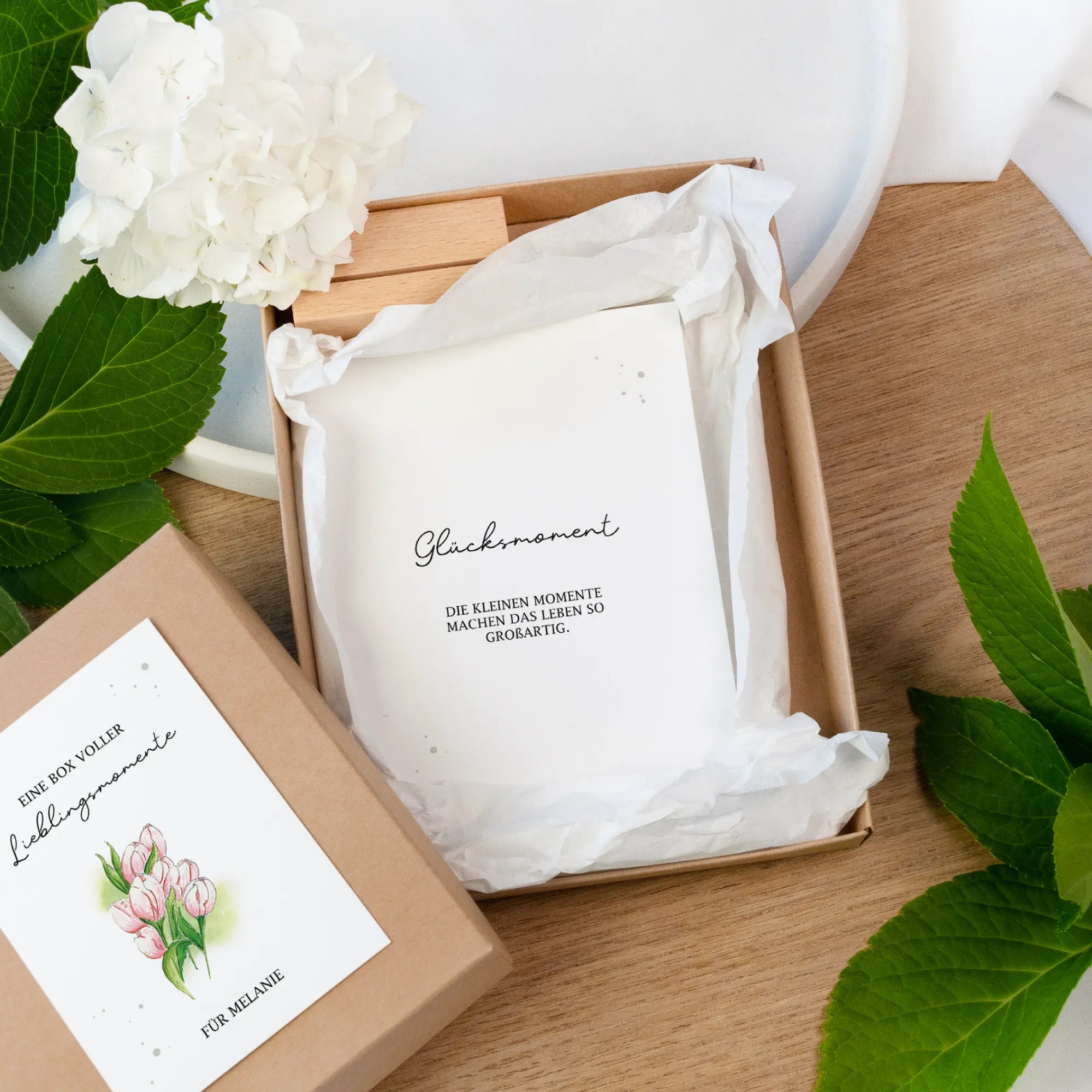 Geöffnete Geschenkbox aus Kraftpapier. Darin liegen Gutscheinkarten mit dem Spruch Lieblingsmoment und ein Kartenhalter.