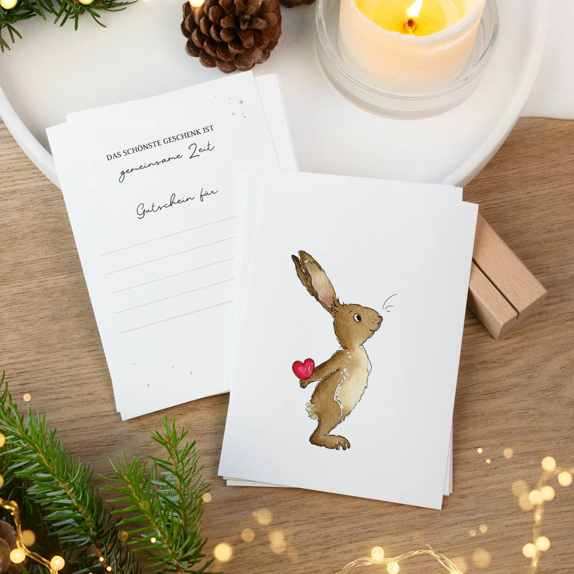 Zwei Gutscheinkarten auf einem Holztisch. Vorne ein handgemaltes Hase Aquarell Motiv und hinten Linien zum Ausfüllen.
