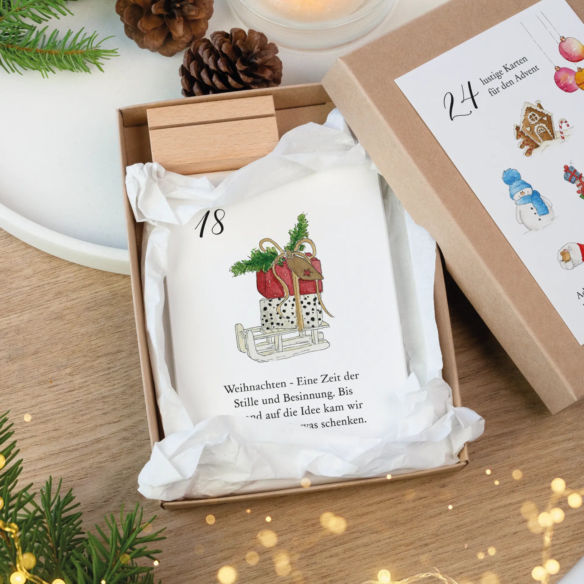 Geöffnete Schachtel mit Adventskalender Karte 18 Schlitten und Päckchen Aquarell Motiv sowie Holz Kartenhalter.