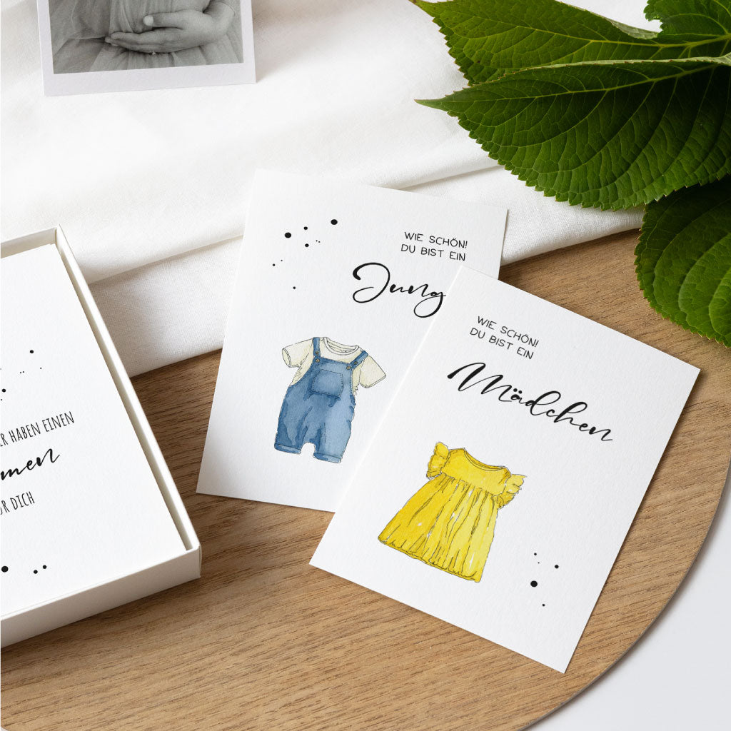 Zwei Aquarellkarten zur Schwangerschaft: gelbes Kleid für Mädchen und blaue Latzhose für Junge – mit liebevoll gestaltetem Text „Wie schön! Du bist ein …“.