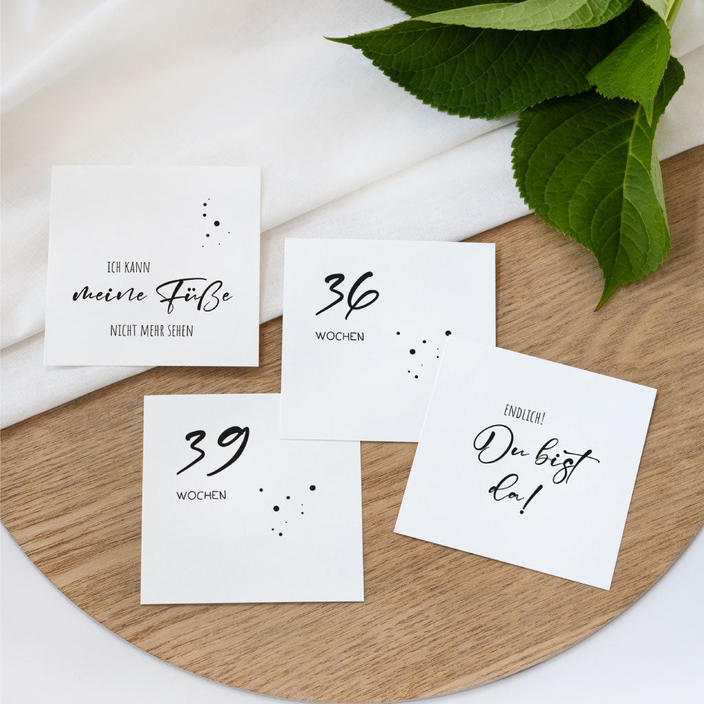 Flach gelegte Schwangerschafts-Wochenkarten mit humorvollen und emotionalen Sprüchen für die späten Schwangerschaftswochen, stilvoll inszeniert auf Holzuntergrund.