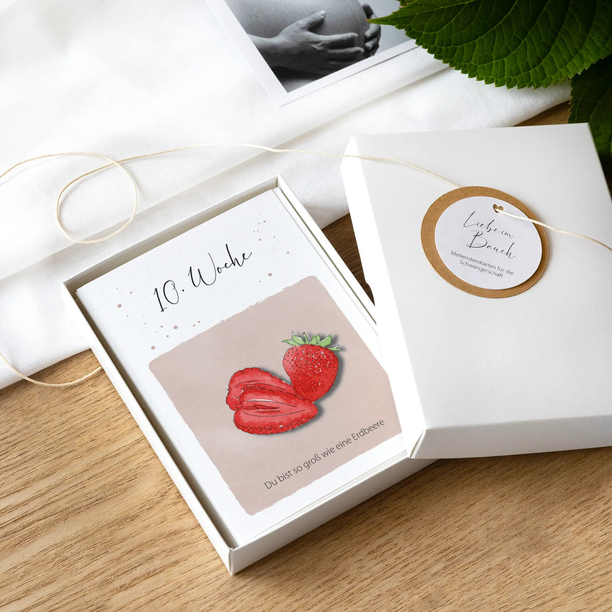 Meilensteinkarten Schwangerschaft in geöffneter Geschenkbox, Karte 10. Woche mit Aquarell Motiv Erdbeere
