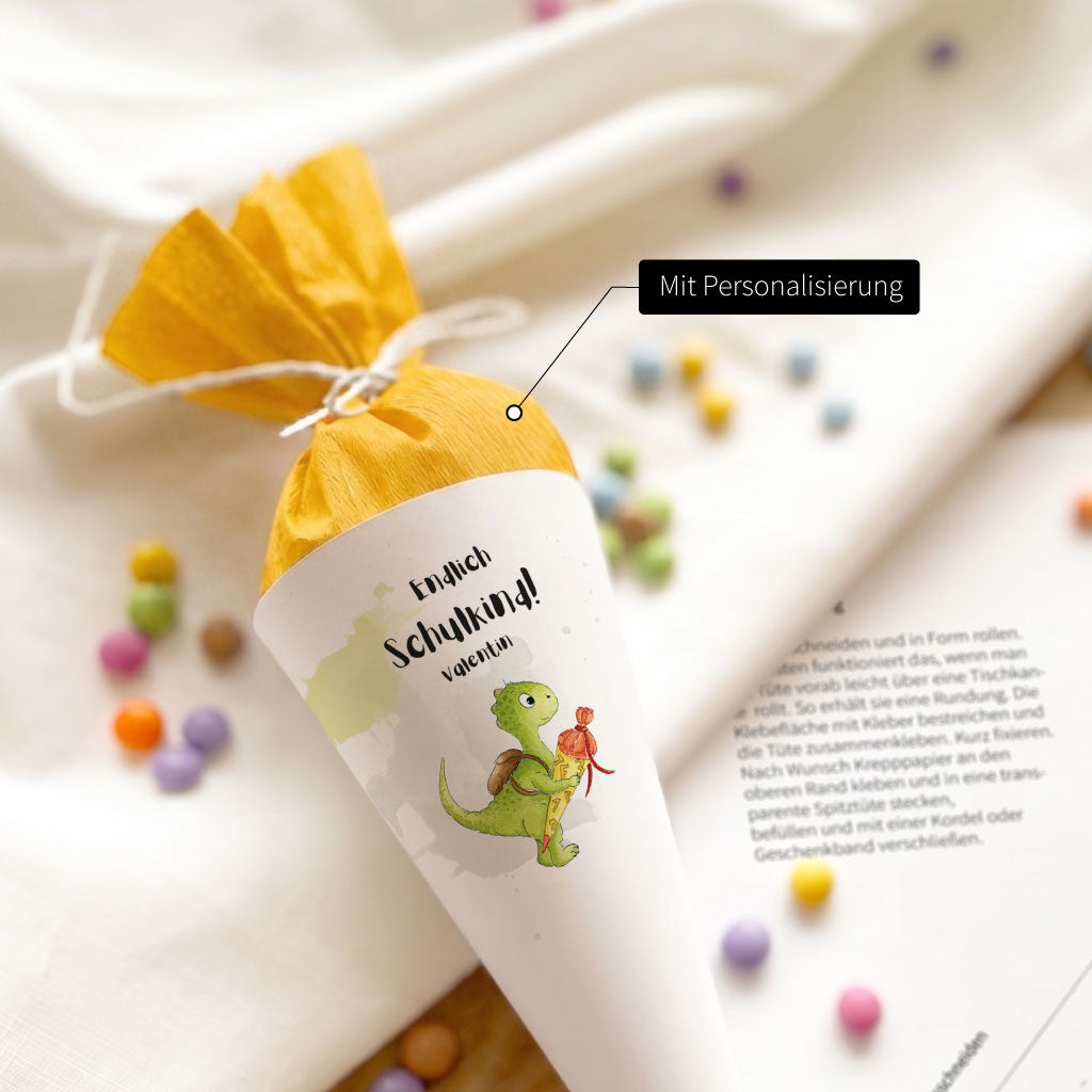 Nahaufnahme einer personalisierten Mini Schultüte mit Dino Aquarell Motiv und gelbem Krepppapier Verschluss.