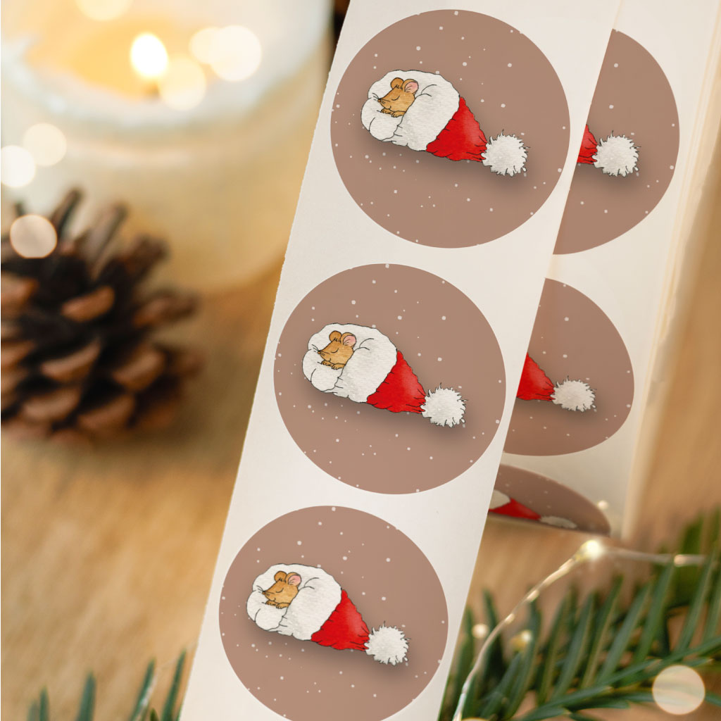 Nahaufnahme einer Stickerrolle mit Aquarell-Aufklebern: Maus in Weihnachtsmannmütze auf schneebedecktem Hintergrund, perfekt zum Verpacken von Weihnachtsgeschenken.