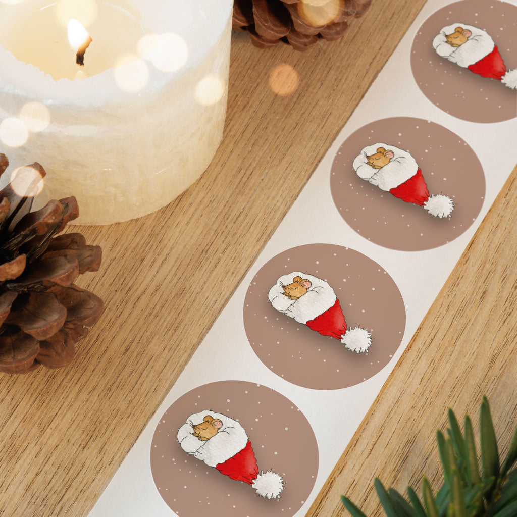 Detailaufnahme von runden Stickern mit Maus in Weihnachtsmannmütze auf einer Rolle – festliche Aufkleber für die Adventszeit und kreative Geschenkverpackungen.
