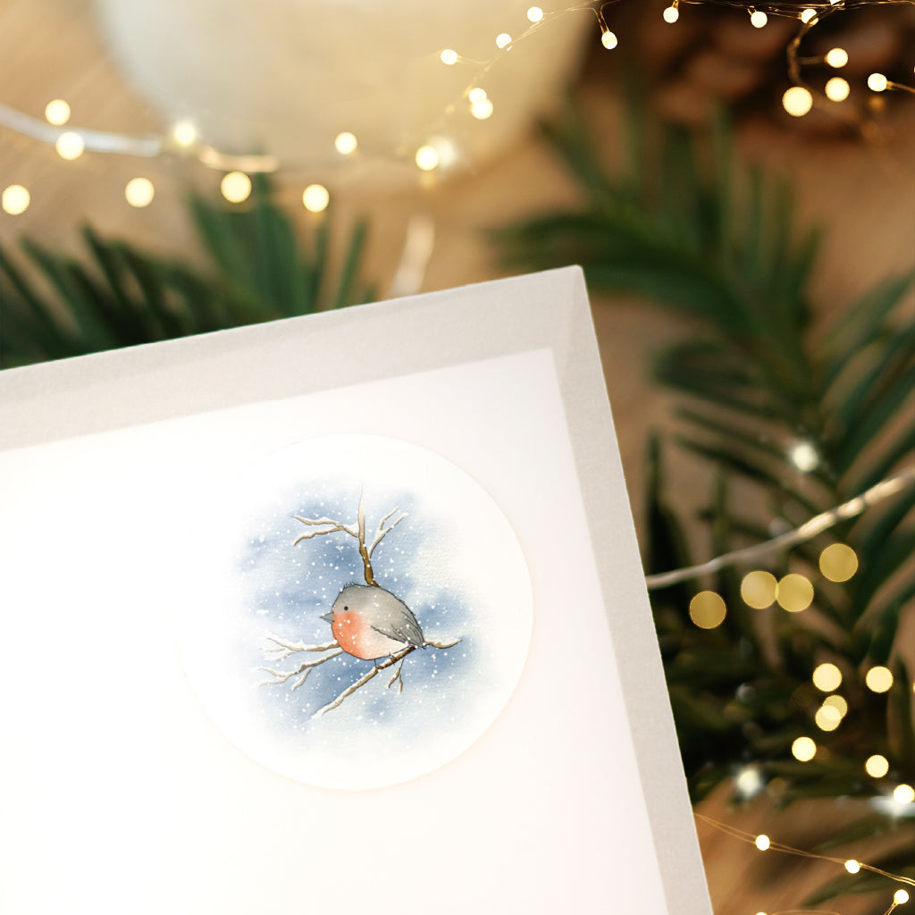 Festlicher Sticker mit einem Rotkehlchen Aquarell Motiv verziert weisse Weihnachtspost im gemütlichen Lichterglanz.