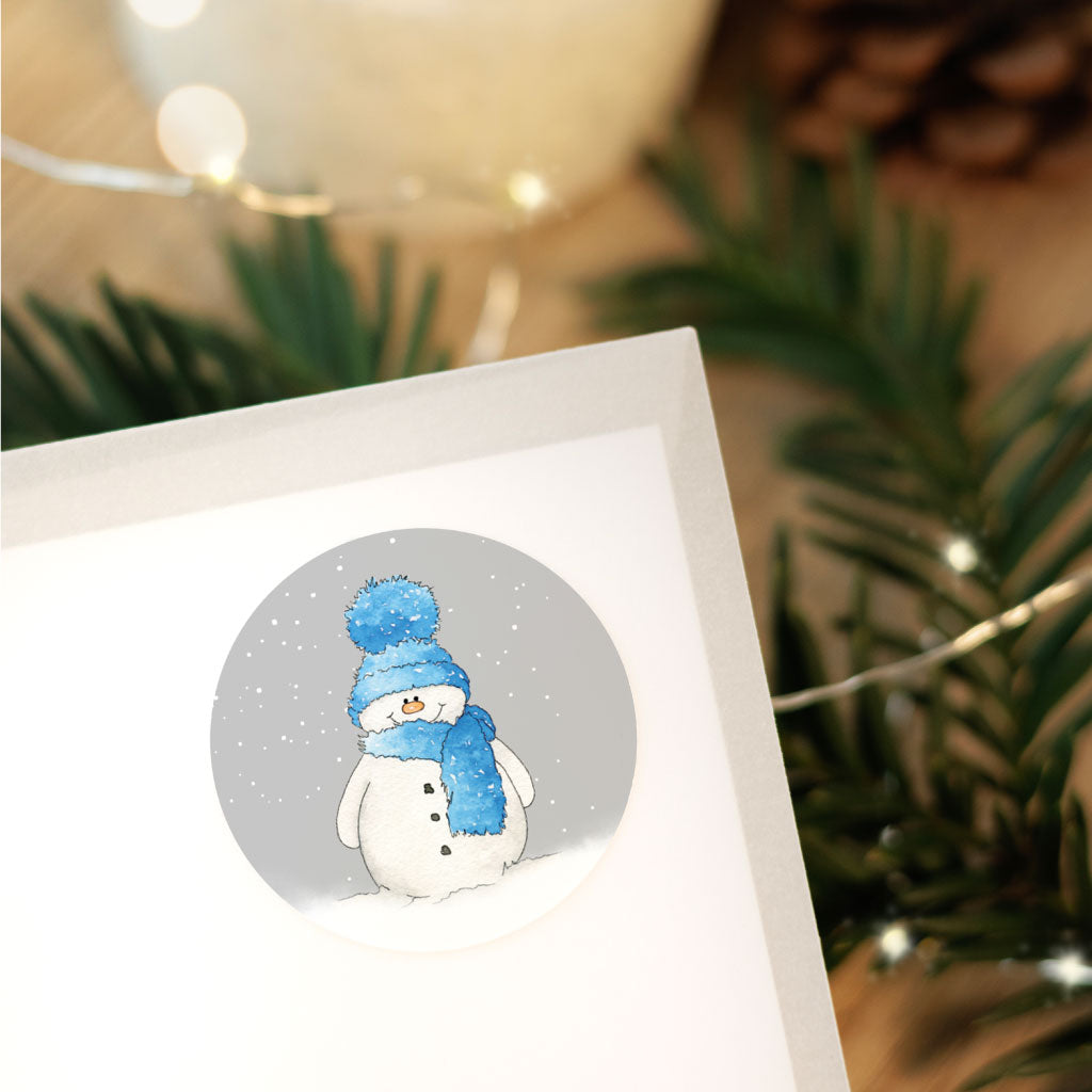 Runder Aufkleber mit handgemaltem Schneemann im Aquarellstil, ideal zur Dekoration von Weihnachtsgeschenken.