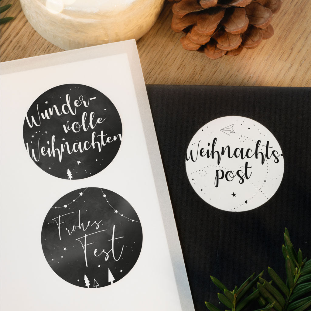 Weihnachtsaufkleber im schwarz weiß Design kleben auf Weihnachtsgeschenk Verpackung, im Hintergrund Weihnachtsdekoration.