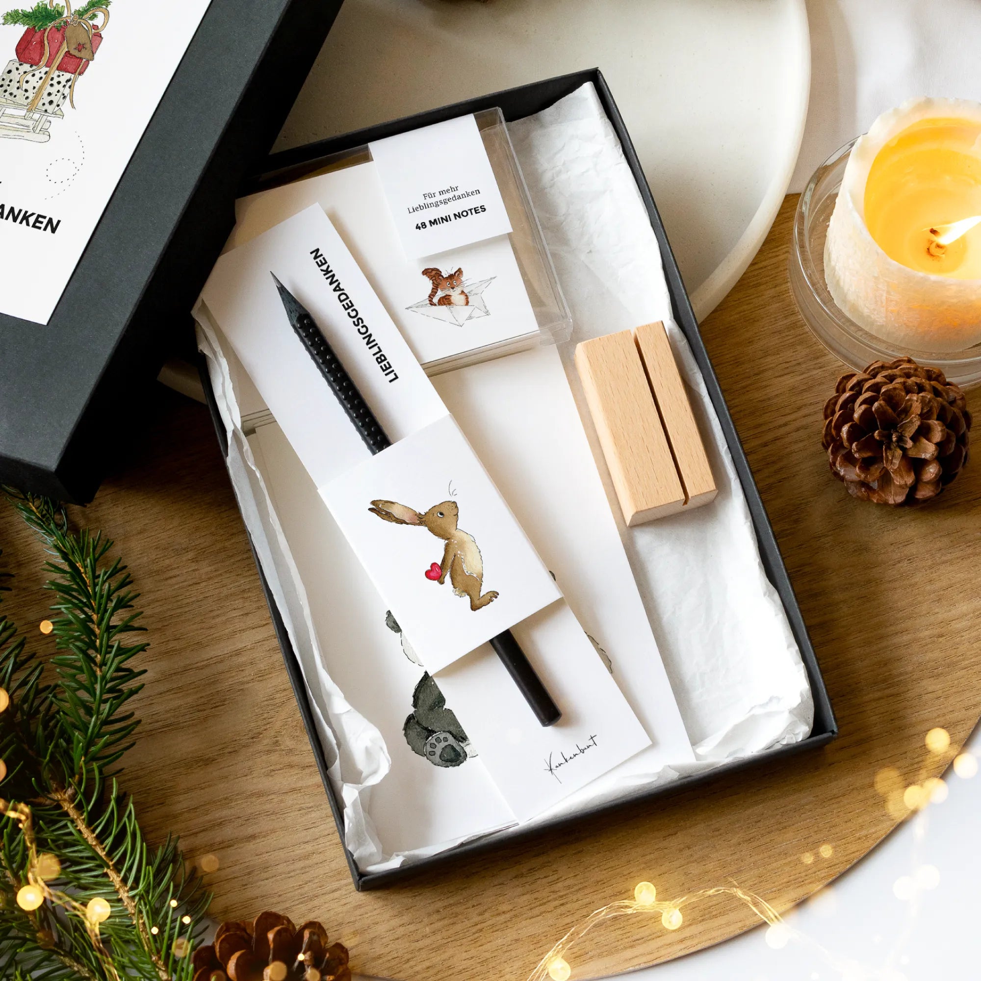 Geöffnete schwarze Geschenkbox Weihnachten mit 12 Karten mit Aquarell Motiv, 48 Mini Notes, Holz-Kartenhalter und schwarzem Design Bleistift