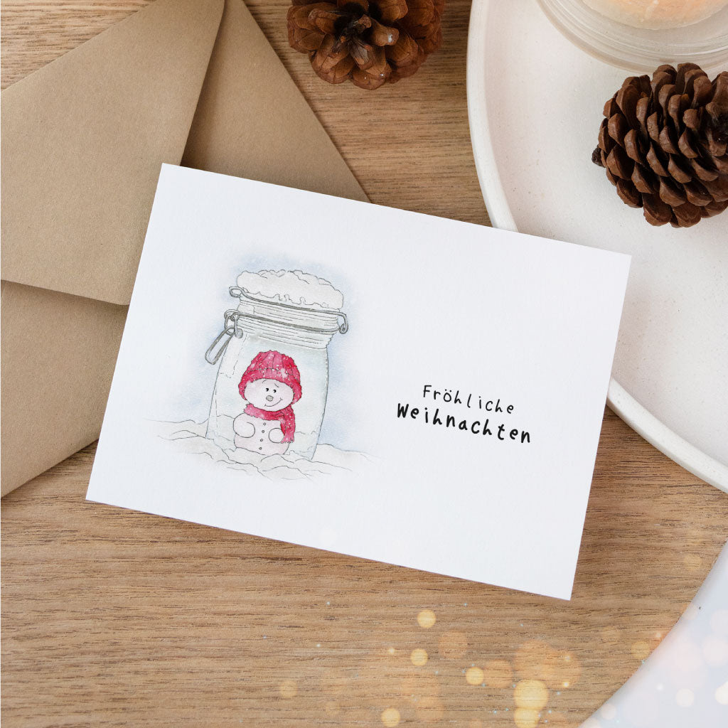 Handgemalte Weihnachtskarte mit Schneemann im Weckglas und Spruch „Fröhliche Weihnachten“, liebevoll gestaltete Aquarell-Postkarte von Funkenbunt.
