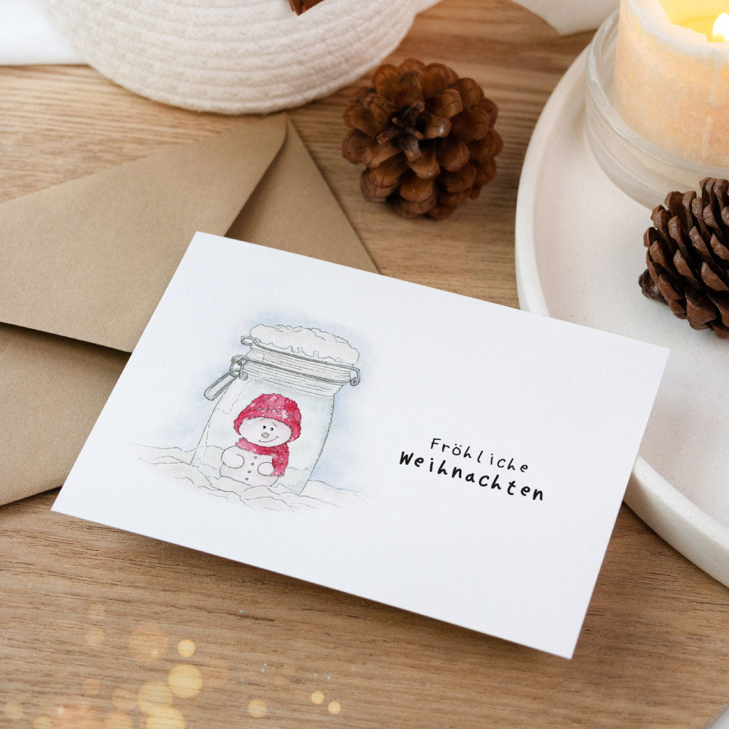 Detailaufnahme der handgemalten Weihnachtskarte mit Schneemann im Glas – individuelle Aquarellkunst, perfekt als Postkarte oder Geschenkbeileger.