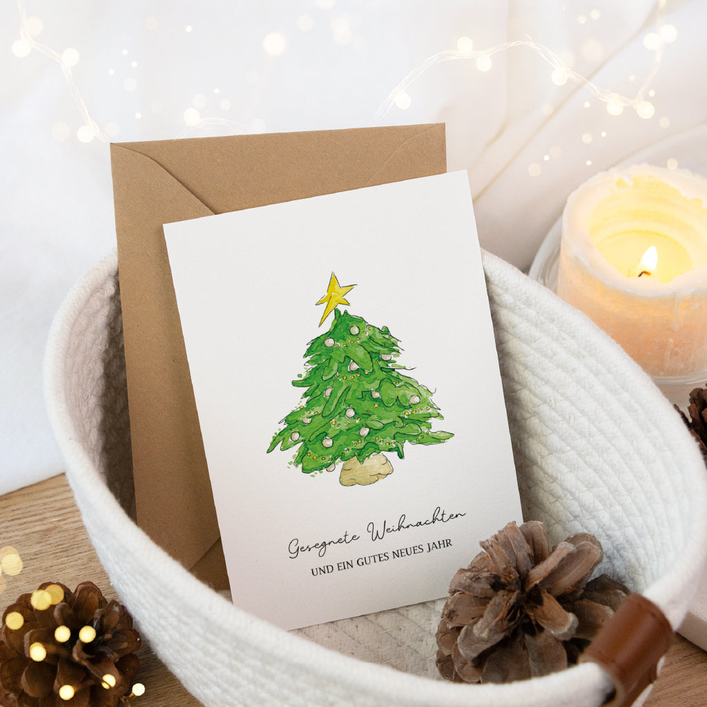 Weihnachtliche Klappkarte mit Tannenbaum Aquarell Motiv in einem hellen Korb dekoriert mit Kerzenschein und Tannenzapfen.