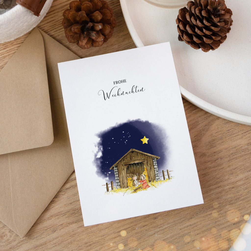 Stimmungsvolle Nahaufnahme einer winterlichen Aquarellkarte mit klassischem Krippenmotiv und passendem Umschlag.