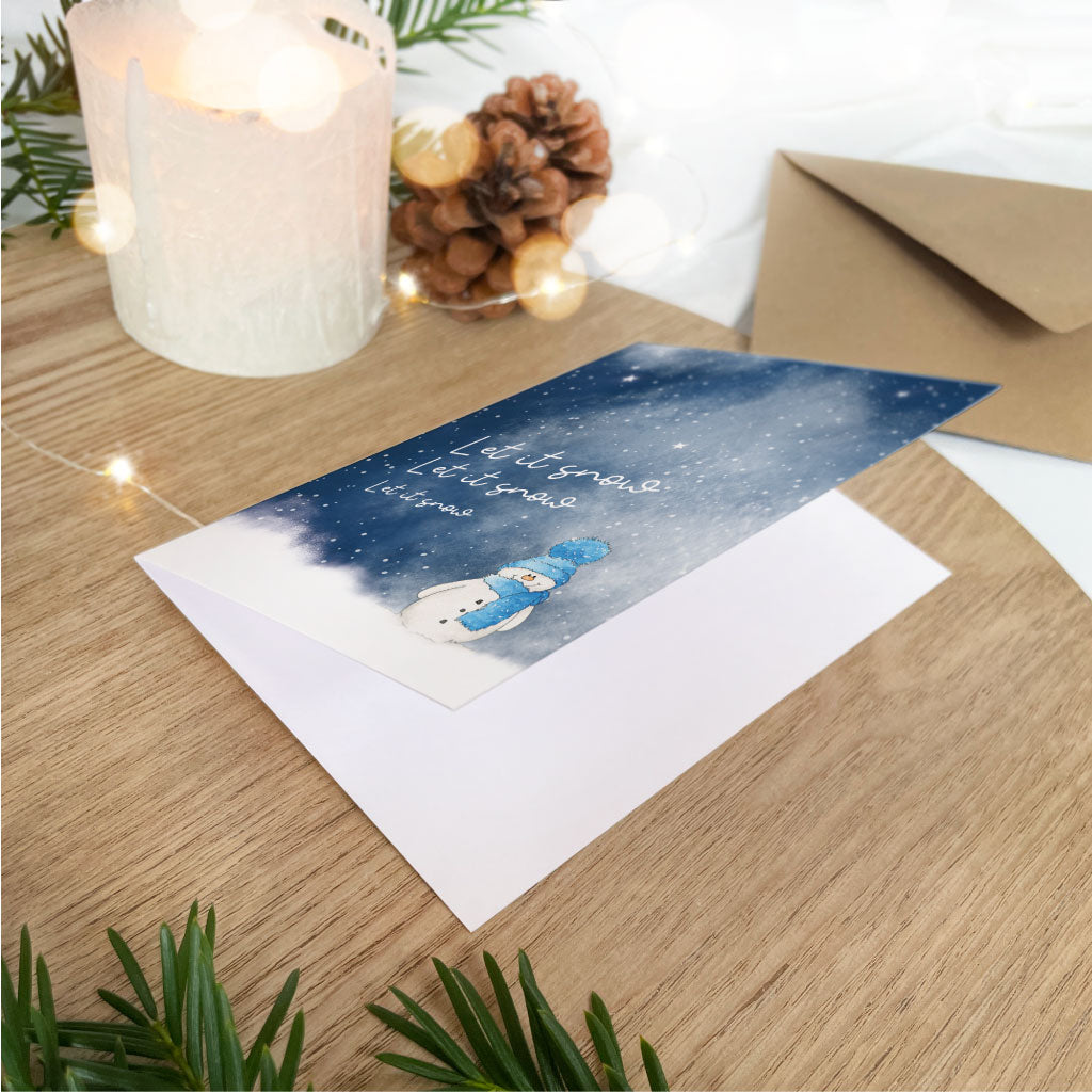 Weihnachtskarte liegt aufgeklappt vor Kraftpapier Kuvert
