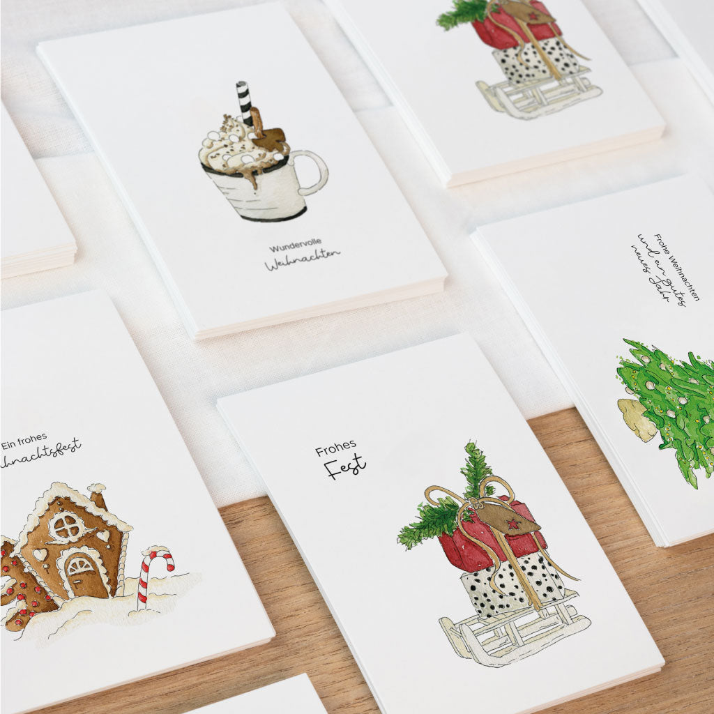 Weihnachtskarten Set mit vier liebevoll gestalteten Grußkarten im Aquarellstil – mit winterlichen Motiven wie Schlitten, Tanne, Lebkuchenhaus und Kakao.