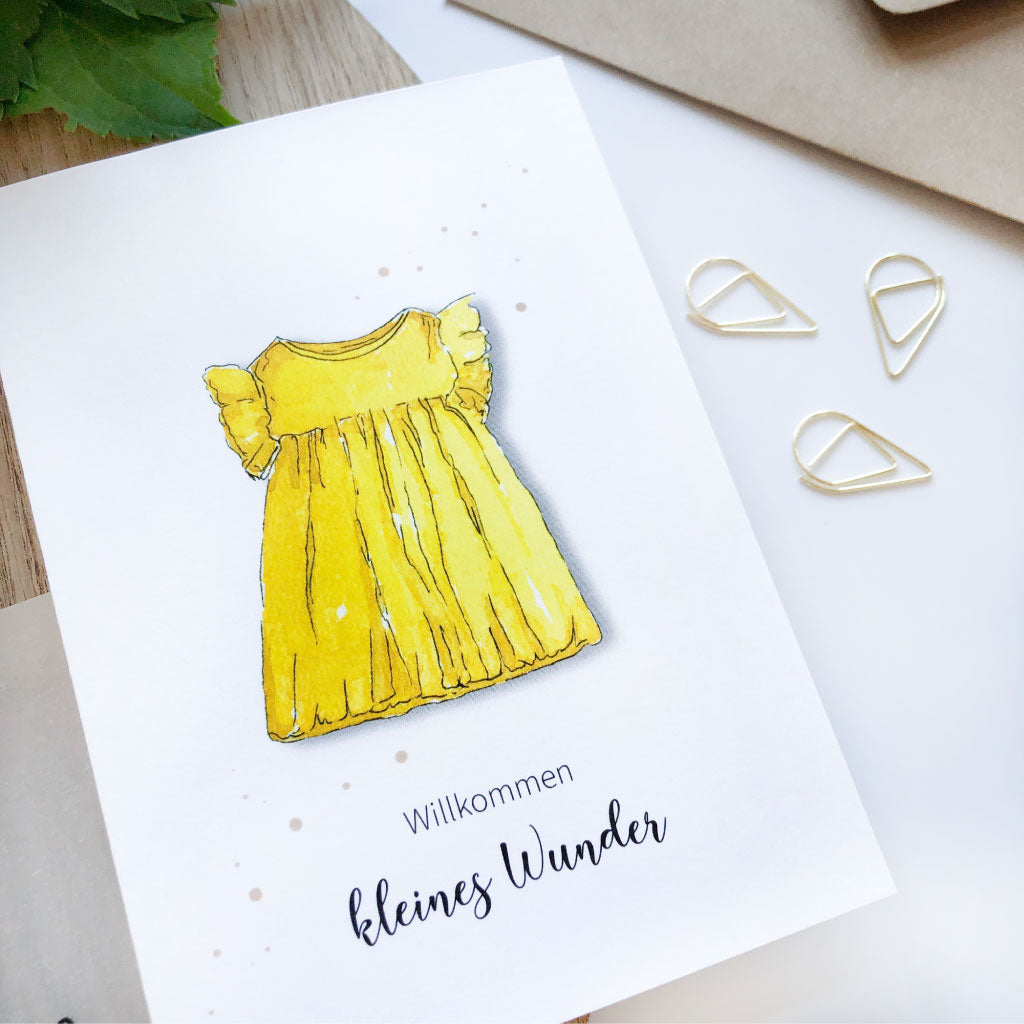 Detailaufnahme Karte mit Aufdruck "Willkommen kleines Wunder" und Kleidchen