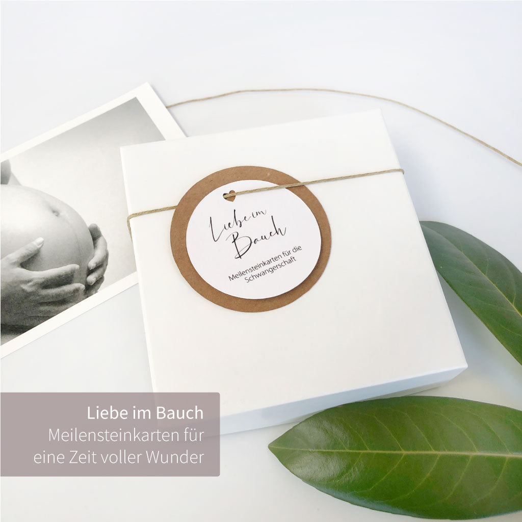 Geschenkschachtel ist geschlossen, umwickelt mit Kordel und Anhänger "Liebe im Bauch"