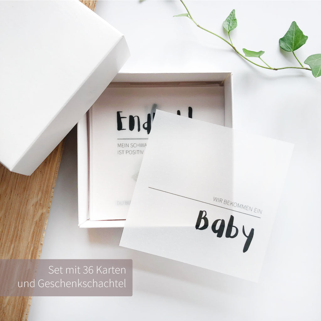 Set mit 36 Karten in weißer Geschenkbox, Karte "Wir bekommen ein Baby" liegt sichtbar obenauf