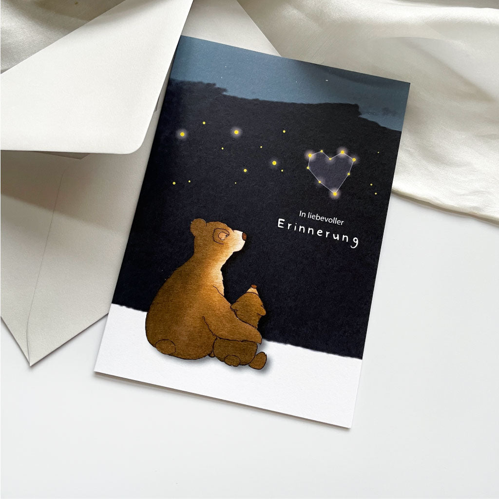 Trauerkarte mit Aquarell Motiv Bären und Sternenhimmel liegt neben hellgrauem Kuvert