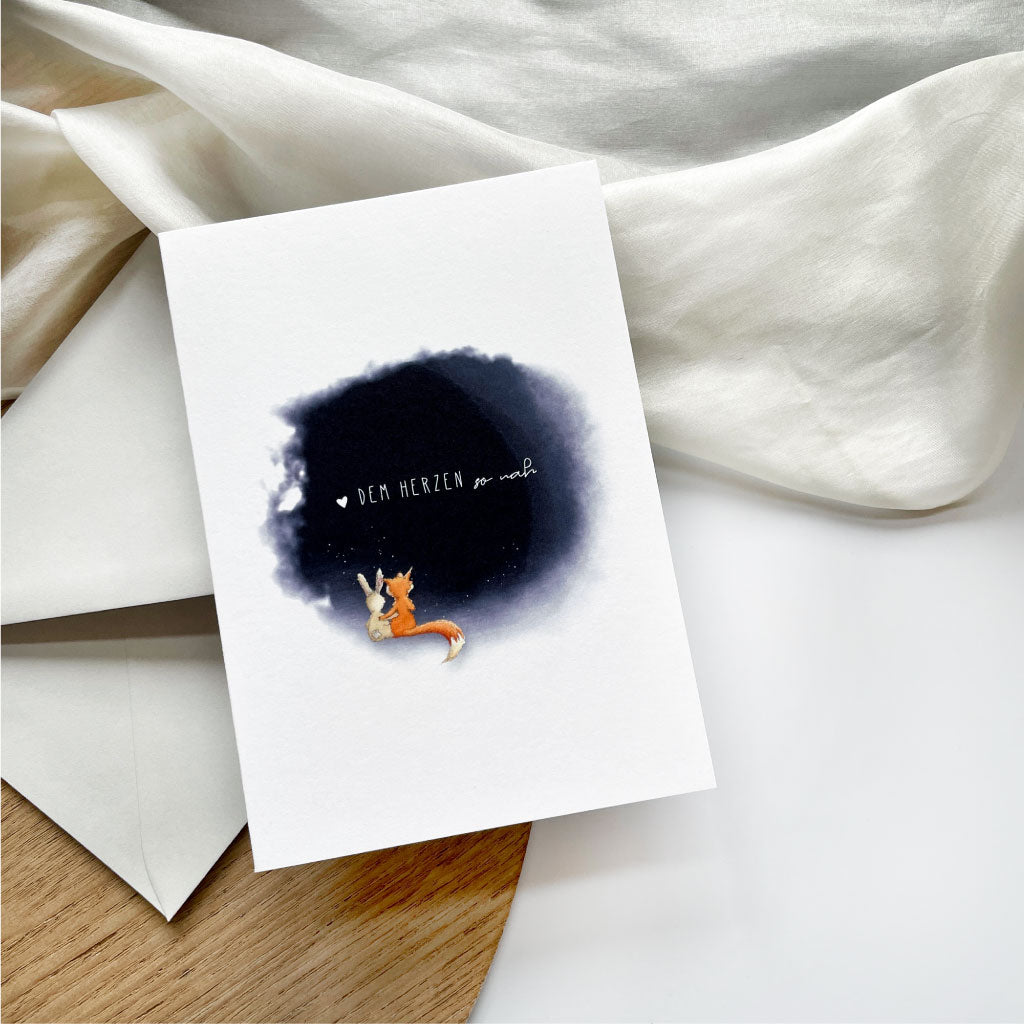 Trauerkarte mit Aquarell Motiv Fuchs und Hase und Trauerspruch liegt auf hellgrauem Kuvert